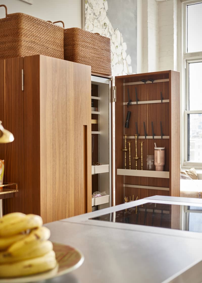 Wooden kitchen cabinet opened showcasing kitchenwares.