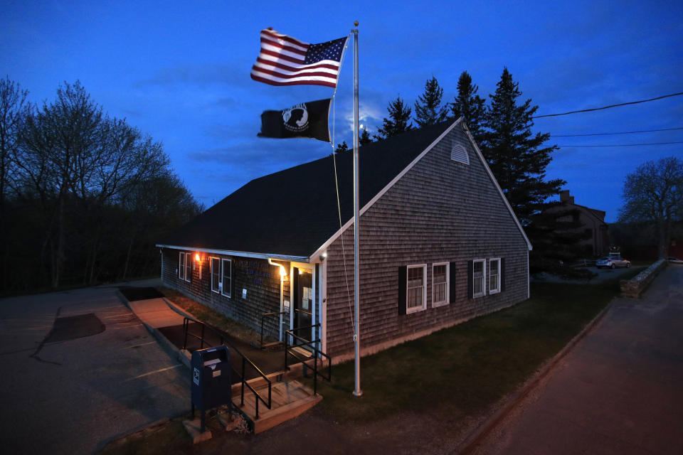 In this Sunday, May 10, 2020, photo a new American flag flies outside the post office on Deer Isle, Maine. The flag was secretly replaced after a plea was posted on the post office bulletin board for help removing the old tattered flag that had been stuck on the pole. "It was really important that the flag be replaced, as a symbol of hope for all of us that there is a new day coming," said community health director Rene Colson Hudson. (AP Photo/Robert F. Bukaty)