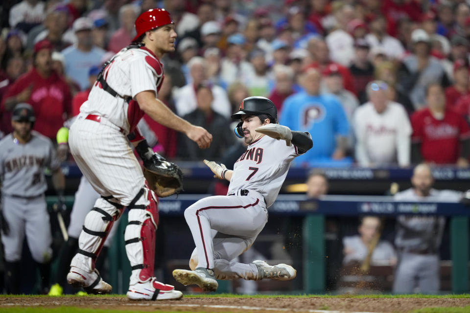 Corbin Carroll, de los Diamondbacks de Arizona, anota frente a J.T. Realmuto, cátcher de los Filis de Filadelfia, en el séptimo juego de la Serie de Campeonato de la Liga Americana, el martes 24 de octubre de 2023 (AP Foto/Matt Slocum)