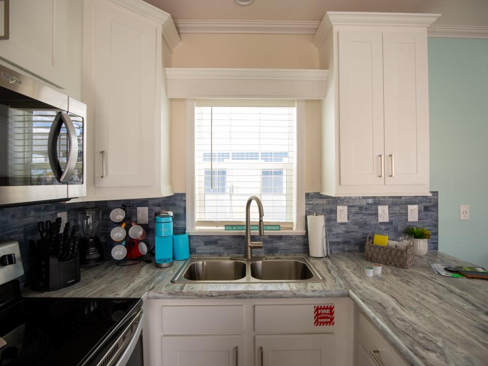 A full kitchen with countertop, stove, microwave, oven, sink, and cabinets.