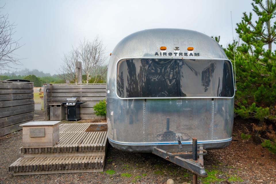 airstream with window in front and small wood deck next to it