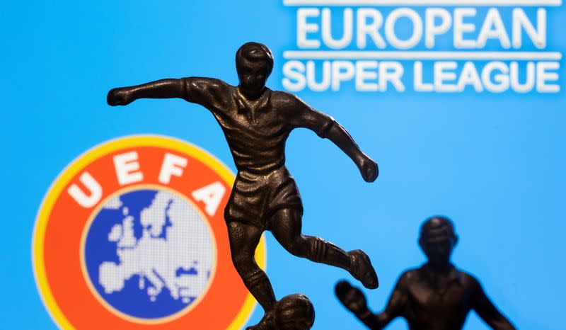 Metal figures of football players are seen in front of the words "European Super League" and the UEFA logo in this illustration