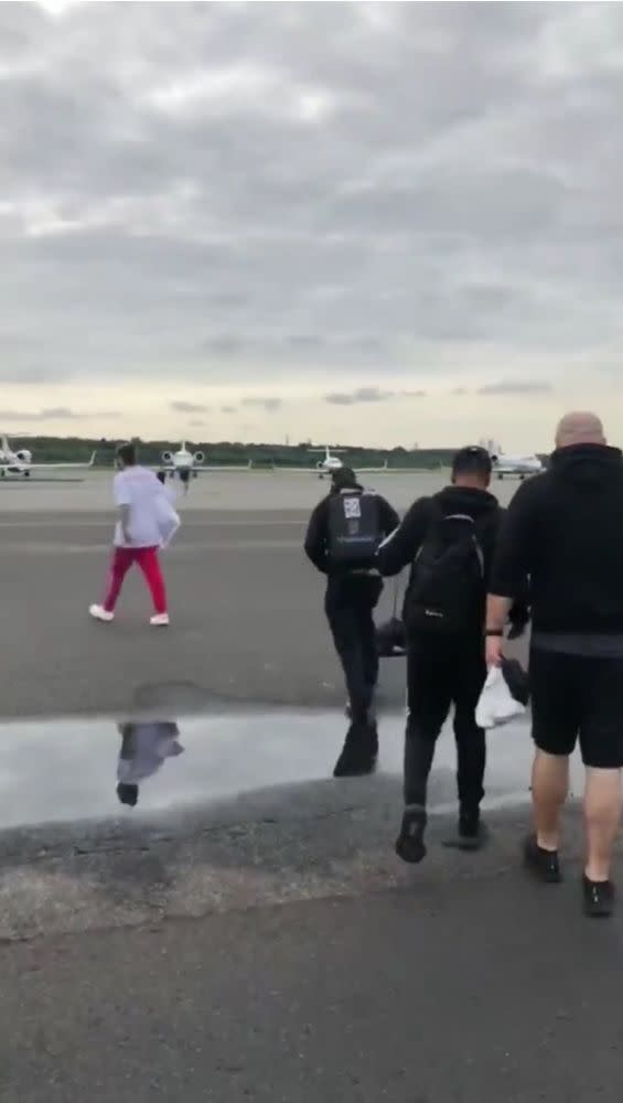 Post Malone (in red pants) walking to the plane Tuesday morning