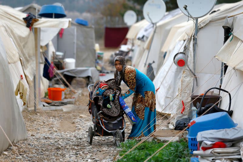 FILE PHOTO: A Syrian refugee mother puts her baby into a stroller in Nizip refugee camp