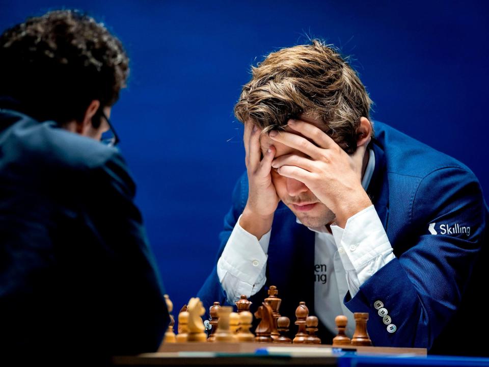 Magnus Carlsen cradles his head in his hands during a chess match in 2021.