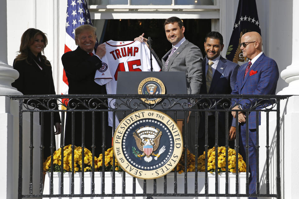 Washington Nationals first baseman Ryan Zimmerman, center, presents a jersey to President Donald Trump during an event to honor the 2019 World Series champion Nationals baseball team at the White House, Monday, Nov. 4, 2019, in Washington. Standing alongside are first lady Melania Trump, left, manager Dave Martinez, second from right, and general manager Mike Rizzo. (AP Photo/Patrick Semansky)