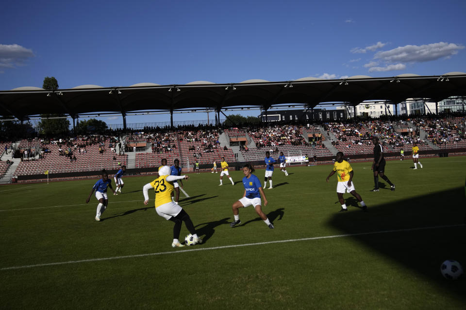 Players challenge during the women's final game of the national cup of working-class neighborhoods betwwen a team representing players with Malian heritage in yellow against one with Congolese roots, in Creteil, outside Paris, France, Saturday, July 2, 2022. This amateur tournament aims to celebrate the diversity of youth from low-income communities with high immigrant populations, areas long stigmatized by some observers and politicians as a breeding ground for crime, riots, and Islamic extremism. (AP Photo/ Christophe Ena)