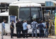 Government agencies gather beside buses to be used to take evacuees to a quarantine facility after arriving in Darwin, Australia, Thursday, Feb. 20, 2020. The evacuees have travelled from Japan after being stranded on the cruise ship Diamond Princess. (Helen Orr/AAP Image via AP)