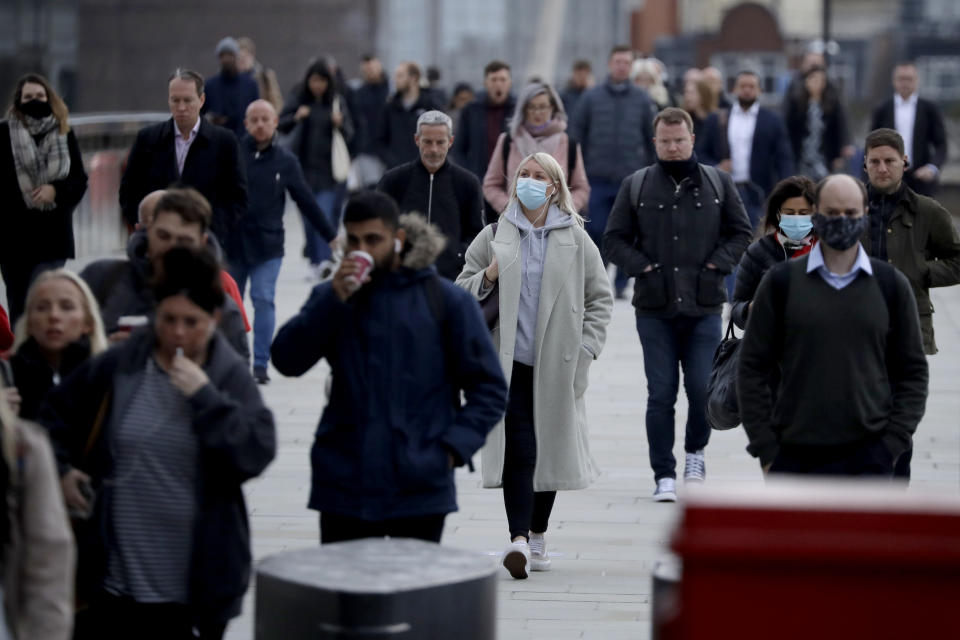 Commuters walk across London Bridge during the morning rush hour towards the offices in the financial district of the City of London, in London, Monday, Oct. 12, 2020. In response to the coronavirus' resurgence, British Prime Minister Boris Johnson is expected to announce in Parliament on Monday a three-tier local lockdown system, formally known as "Local COVID Alert Levels," for England, his office said. (AP Photo/Matt Dunham)