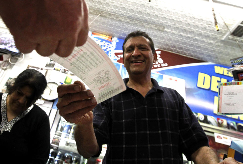 As he hands over a customer's lottery ticket, Keith Ganatra, right, and his wife Anita Ganatra, left, owners of the Del Monte Market, help the long line of customers inside their store waiting to buy Powerball lottery tickets Wednesday, Nov. 28, 2012, in Phoenix. There has been no Powerball winner since Oct. 6, and the jackpot has already reached a record level for the game of over $550 million. (AP Photo/Ross D. Franklin)