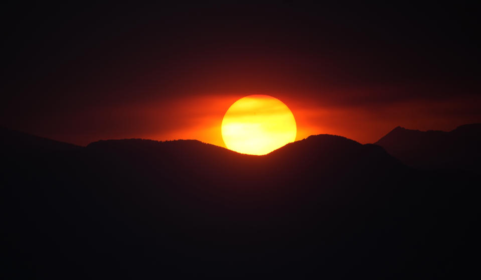 FILE - The suns sets behind the Rocky Mountains after daytime high temperatures reached above 90-degrees Fahrenheit, 32 Celsius, Monday, June 26, 2023, in Denver. As the heat breaks records, weakening and sickening people, it’s worth remembering that dire heat waves have inspired effective efforts to prevent heat illness. (AP Photo/David Zalubowski, File)