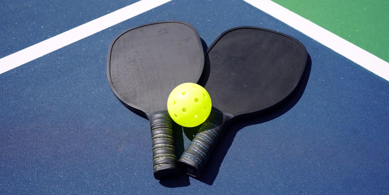 pickleball paddles and yellow ball on court