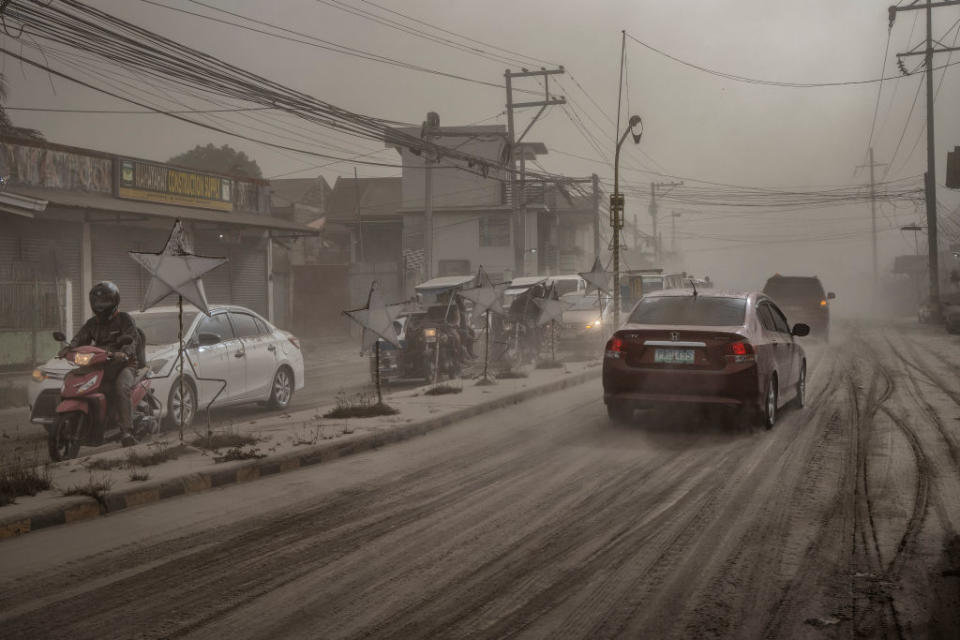 Motorists drive through a road covered in volcanic ash from Taal Volcano's eruption in Lemery, Batangas province, Philippines on Jan. 13, 2020. | Ezra Acayan—Getty Images