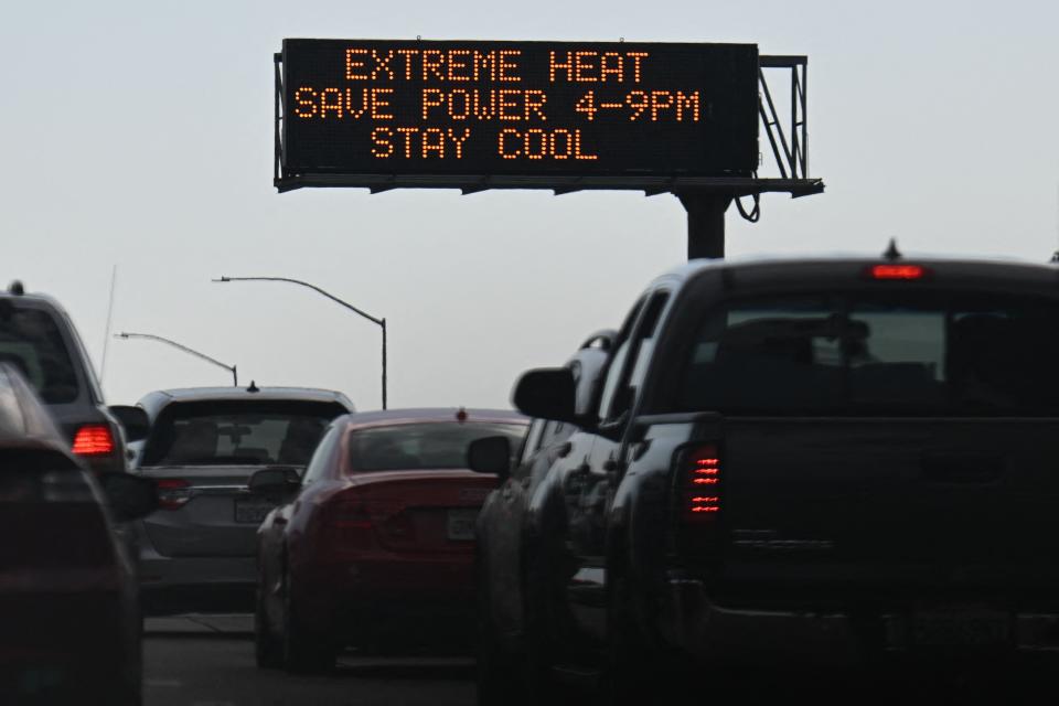 Vehicles drive past a sign on the 110 Freeway warning of extreme heat and urging energy conservation during a heat wave in downtown Los Angeles, California on September 2, 2022.