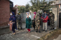 Soldiers stand guard as Kashmiris enter a polling booth area to cast their votes during the first phase of District Development Councils election on the outskirts of Srinagar, Indian controlled Kashmir, Saturday, Nov. 28, 2020. Thousands of people in Indian-controlled Kashmir voted Saturday amid tight security and freezing cold temperatures in the first phase of local elections, the first since New Delhi revoked the disputed region's semiautonomous status. (AP Photo/Mukhtar Khan)