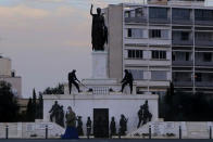 A Christian Orthodox priest wearing a face mask, talks from his cell phone as walks in front of the Liberty monument in central capital Nicosia, Cyprus, Wednesday, Jan. 27, 2021. Cyprus' health minister Constantinos Ioannou said that the first to re-open as of Feb. 1st will be hair and beauty salons followed a week later by retail stores, shopping malls and elementary schools. Students in their final year of high school will also go back to classes on Feb. 8. (AP Photo/Petros Karadjias)