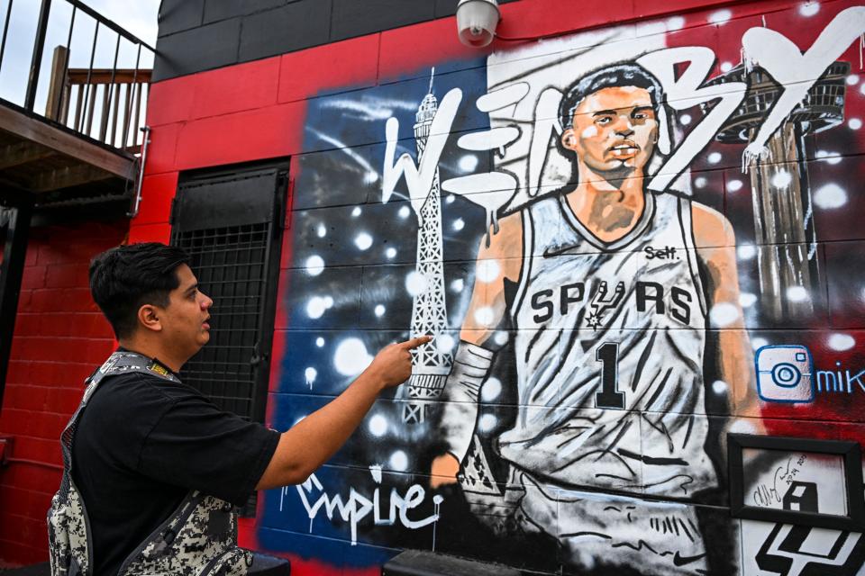 Digital artist Soy Empire stands in front of the mural he designed of San Antonio center Victor Wembanyama in San Antonio, Texas.