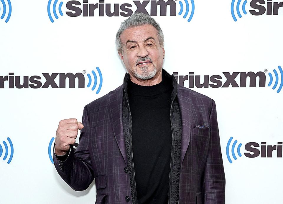 Sylvester Stallone holds his fist up at a red carpet event