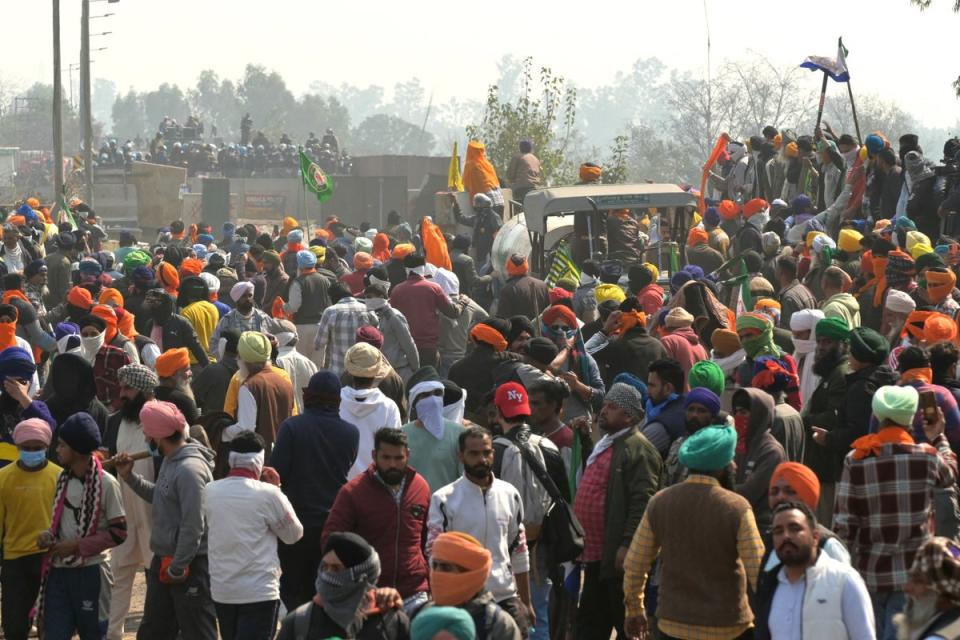 Police and Rapid Action Force (RAF) personnel (behind) block a highway to prevent farmers (front) from marching towards New Delhi (AFP via Getty Images)
