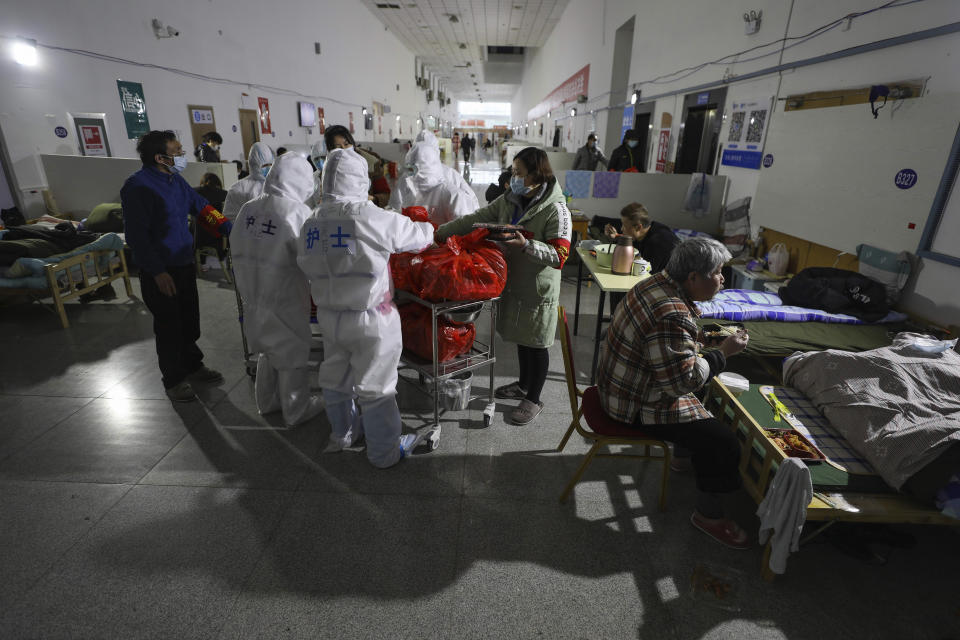 In this Friday, Feb. 21, 2020, photo, volunteers and nurses distribute meals to patients at a temporary hospital at Tazihu Gymnasium in Wuhan in central China's Hubei province. China's leadership sounded a cautious note Friday about the country's progress in halting the spread of the new virus that has now killed more than 2,200 people, after several days of upbeat messages. (Chinatopix via AP)