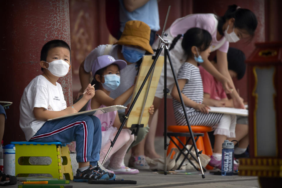 Children wearing face masks to protect against the coronavirus sketch the Temple of Heaven in Beijing, Saturday, July 18, 2020. Authorities in a city in far western China have reduced subways, buses and taxis and closed off some residential communities amid a new coronavirus outbreak, according to Chinese media reports. They also placed restrictions on people leaving the city, including a suspension of subway service to the airport. (AP Photo/Mark Schiefelbein)