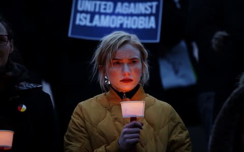 A woman carries a candle at a vigil for victims of the mosque shootings in New Zealand, - Credit: REUTERS