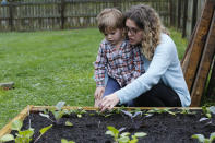 Stephanie Owens looks over the garden with her son, Cole, as they tend to it at their home Wednesday March 25 , 2020, in Glen Allen, Va. Owens is a pharmacist who has had to continue to go to work, but has been able to spend more time with her kids because they are home from school . One of the activities that they have done is planting the garden. (AP Photo/Steve Helber)