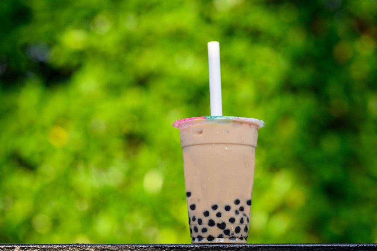 Image of A plastic cup of fresh milk with brown sugar boba drinks with green background