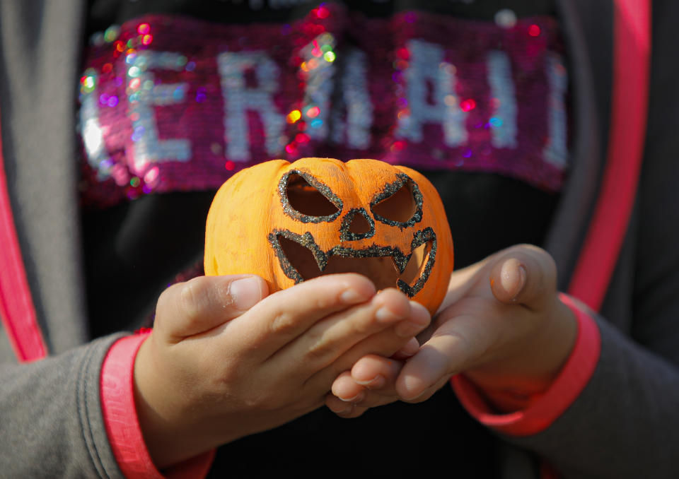 In this Saturday, Oct. 26, 2019 photo a child holds a carved pumpkin at The Halloween Pumpkin Fest in Bucharest, Romania. (AP Photo/Vadim Ghirda)