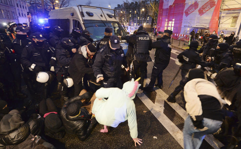 Police confront protesters in front of the Education Ministry building in Warsaw, Poland, on Monday Nov. 23, 2020. Police detained several people as women-led protests over abortion rights flared up in Warsaw and elsewhere in Poland. The protests, organized by the group Women's Strike, have been occurring regularly since the constitutional court issued an Oct. 22 ruling that further tightens an abortion law that was already one of the most restrictive in Poland.(AP Photo/Czarek Sokolowski)