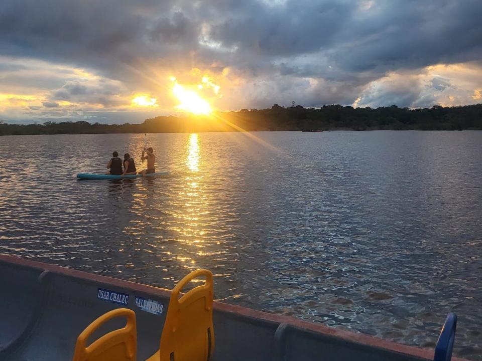 sun setting over a body of water in the amazon rainforest