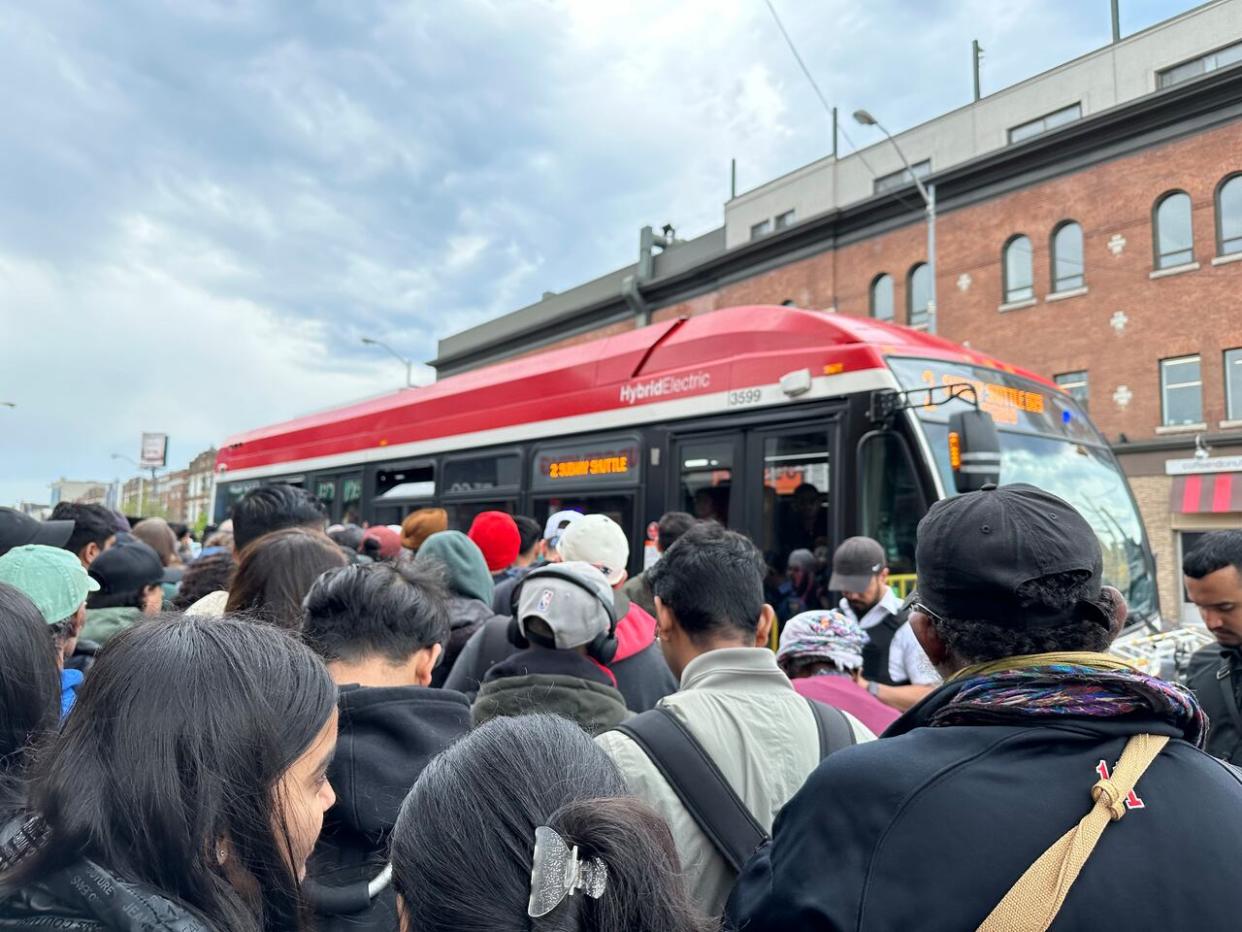 TTC customers crowd together as a shuttle bus approaches on Danforth Avenue near Broadview Avenue. (Muriel Draaisma/CBC - image credit)