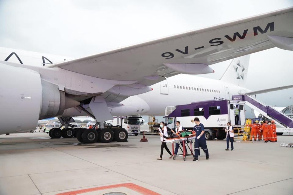 A person is seen on a stretcher being carried away from a Singapore Airlines Boeing 777