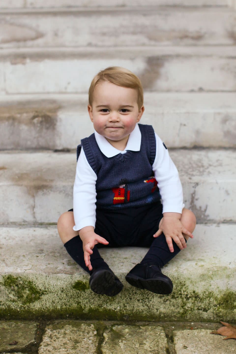 <p>Prince George sits on the steps of Kensington Palace ahead of his first-ever Christmas with the royal family in December 2014. The photo, which features George in a jumper with a guardsman pattern, was part of a trio taken by Prince Harry's private secretary Edward Lane Fox.</p>