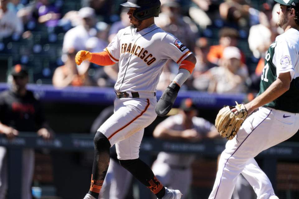 San Francisco Giants' Thairo Estrada, left, scores on a wild pitch thrown by Colorado Rockies relief pitcher Karl Kauffmann in the third inning of the first baseball game of a doubleheader, Saturday, Sept. 16, 2023. (AP Photo/David Zalubowski)