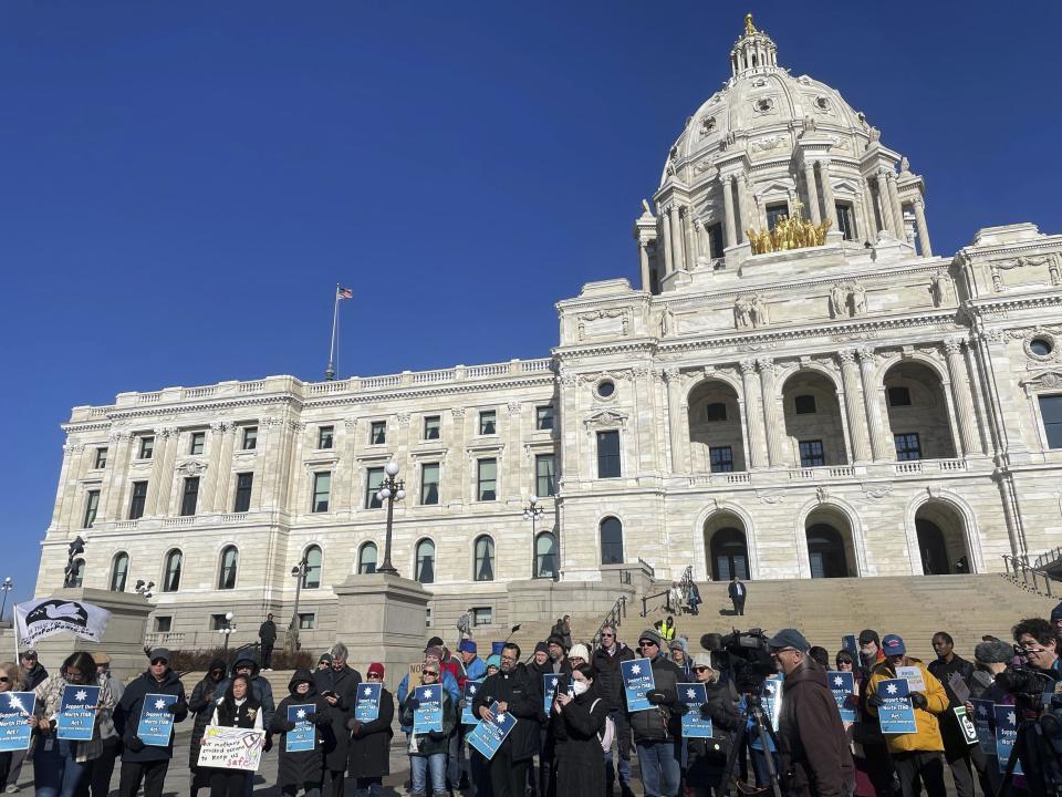 Dozens of people held blue signs that read, "Support the North Star Act!" at a rally in front of the state capitol building in St. Paul, Minn., on Monday, Feb. 12, 2024, the first day of Minnesota's legislative session for the year. If passed, the North Star Act legislation would make Minnesota a "sanctuary state" for immigrants without permanent legal status by prohibiting state and local governments from sharing data or collaborating with federal authorities on civil immigration enforcement. (AP Photo/Trisha Ahmed)