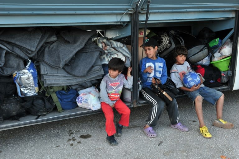 Children sit on a bus as they wait to board in order to leave the refugee and migrant makeshift camp on the Greek-Macedonia border near the village of Idomeni on May 23, 2016