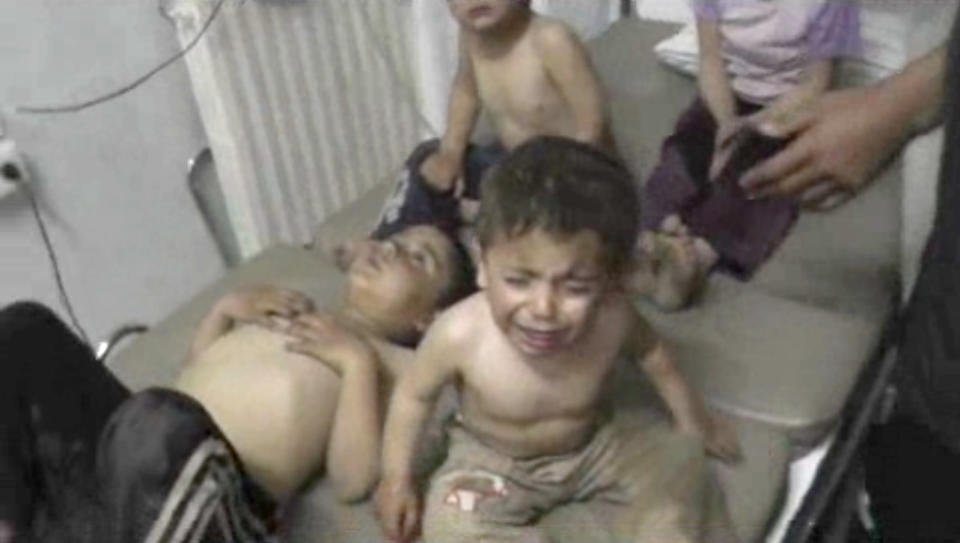 In this Friday, April 11, 2014 image made from amateur video, provided by Shams News Network, a loosely organized anti-Assad group based in and out of Syria that claim not to have any connection to Syrian opposition parties or any other states, and is consistent with independent AP reporting, shows a child crying as he sits on a bed with others, in Kfar Zeita, some 200 kilometers (125 miles) north of Damascus, Syria. Syrian government media and rebel forces said Saturday, April 12, 2014 that poison gas had been used in the village on Friday, injuring scores of people, while blaming each other for the attack. (AP Photo/Shams News Network)