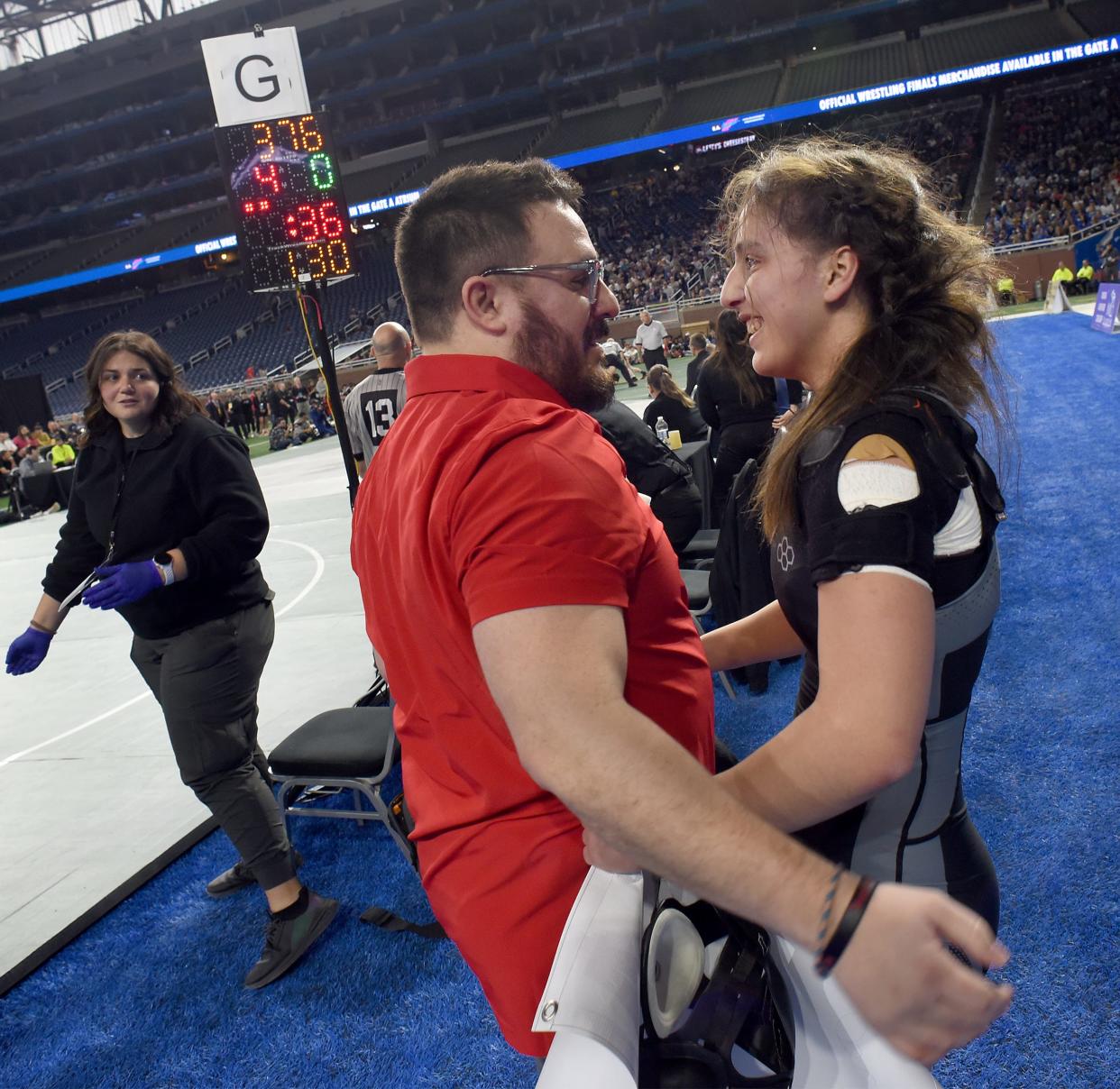 Milan's Angelina Pena is hugged by her coach Adam Caballero after winning her fourth state individual wrestling champoinship at Ford Field in Detroit on Saturday, March 2, 2024.