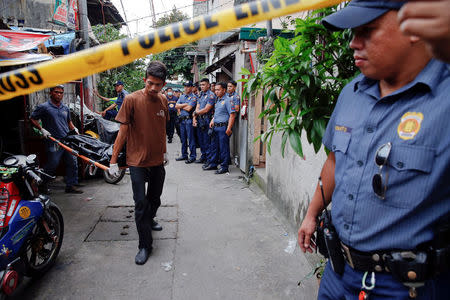 Police gather in an alley as the bodies of Noberto Maderal and fellow pedicab driver George Avancena, killed during a drug-related police operation, are taken by funeral parlour workers in Manila, Philippines October 19, 2016. REUTERS/Damir Sagolj
