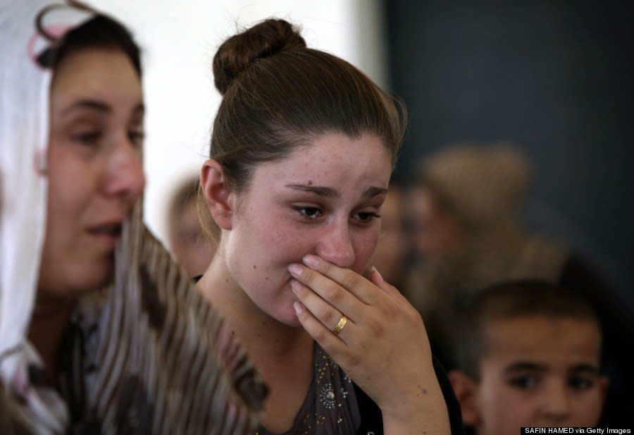 A Yazidi woman who fled violence cries as she stands among other displaced persons in Dohuk on August 5, 2014. (SAFIN HAMED/AFP/Getty Images)