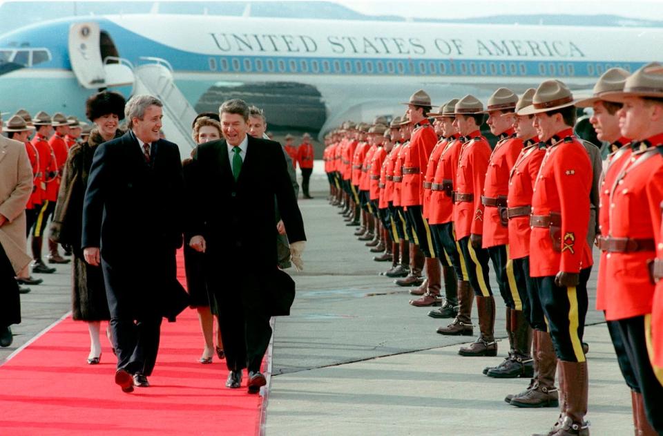 Prime Minister Brian Mulroney and President Ronald Reagan walk past a line of Royal Canadian Mounted Police, March 17, 1985, at the Quebec City airport.  Following are Mrs. Mila Mulroney and Mrs. Nancy Reagan.