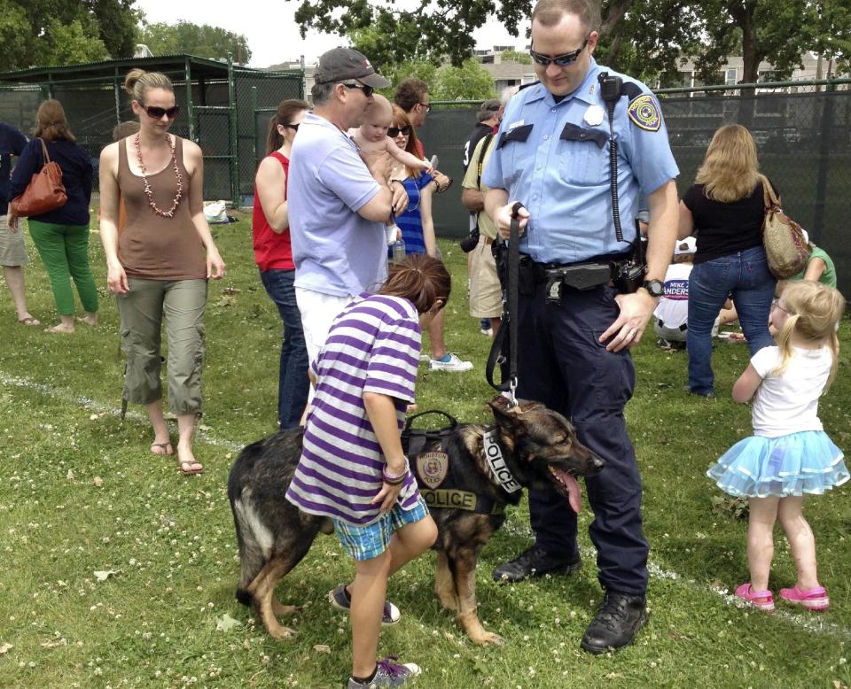 This April 28, 2013 photo provided by K9s4KIDS, Houston Police officer Matt Barnet and his dog Aiko take part in a K9s4COPS charity softball tournament in Houston. Schools have beefed up security, staged mock drills and added metal detectors, cameras and alarms to prevent violence. Some think teachers should be armed and the National Rifle Association wants armed police in every American school. Kristi Schiller thinks some special dogs might do the trick. She wants her charity, K9s4KIDS, to do for schools what it’s done for police departments in the U.S. - place scores of trained dogs among their ranks through the nonprofit set up in 2009. (AP Photo/K9s4KIDS, Veronica Schiller)