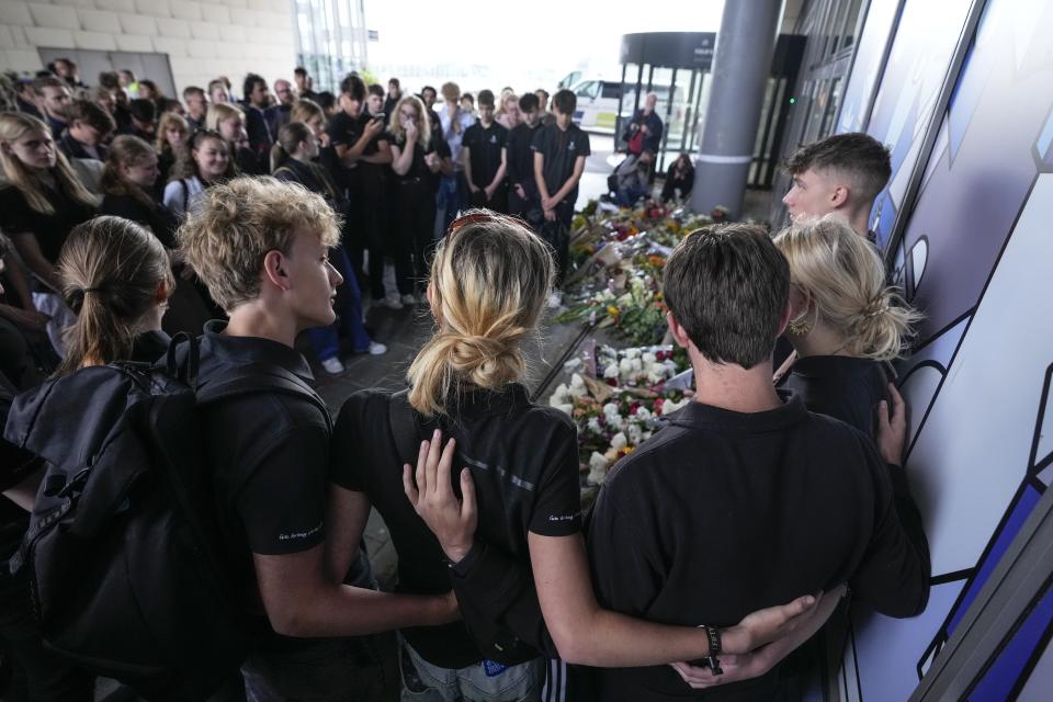 People gather to lay flowers at the entrance of the Field's shopping center in Copenhagen, Denmark, Tuesday, July 5, 2022. Police say a gunman who killed three people when he opened fire in a crowded shopping mall acted alone and apparently selected his victims at random. They all but ruled out that Sunday's attack was related to terrorism. Authorities on Monday filed preliminary charges of murder and attempted murder against a 22-year-old Danish man. (AP Photo/Sergei Grits)