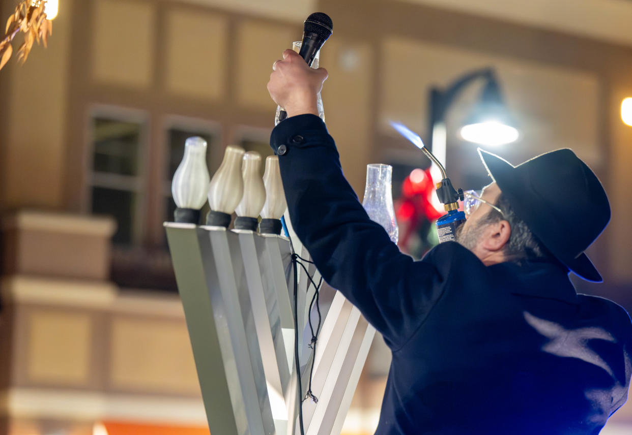 Rabbi Mendel, of Chabad Lubavitch of Doylestown, leads the Hanukkah celebration with the menorah lighting at the Shops of Valley Square in Warrington on Thursday night. Festivities featured songs, a bubble show, a gelt drop and traditional treats.