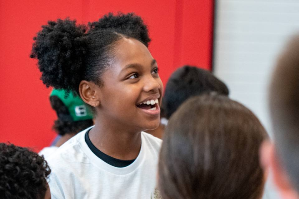 A girl smiles after winning a game at a youth basketball clinic.