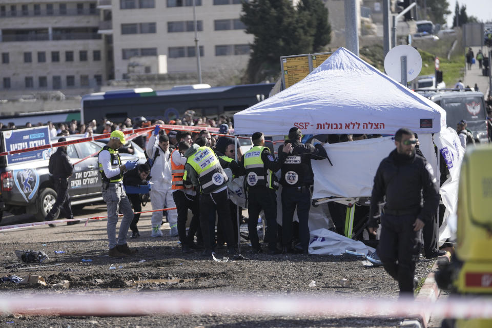 Members of Zaka Rescue and Recovery team work at the site of a car-ramming attack at a bus stop in Ramot, a Jewish settlement in east Jerusalem, Friday, Feb. 10, 2023. A suspected assailant rammed his car into several pedestrians in east Jerusalem on Friday. Police said that the suspected attacker was shot at the scene. There was no immediate word on his condition. Police identified the ages of the injured children as 5 and 6. (AP Photo/Mahmoud Illean)