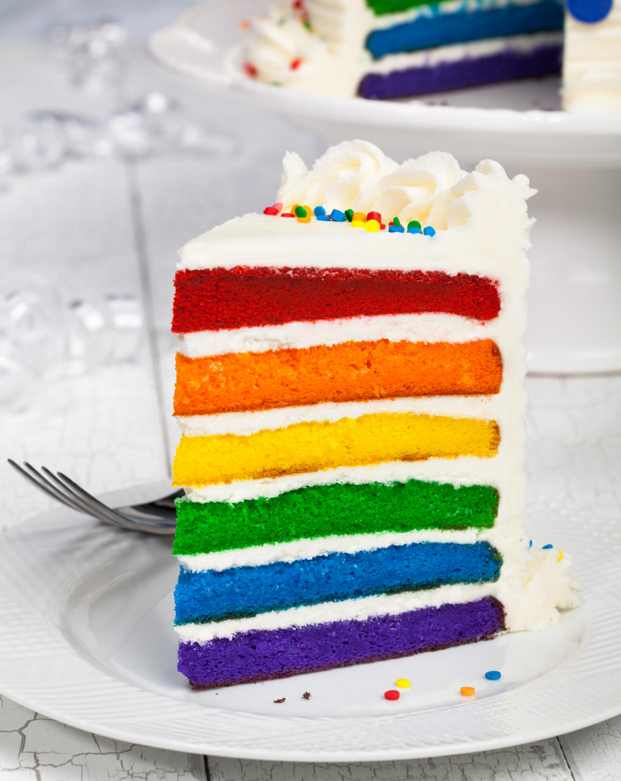 Slice of colourful rainbow layered birthday cake.