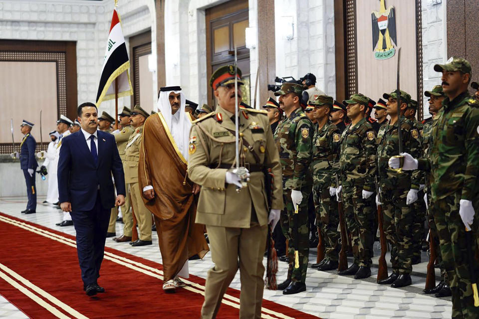 This photo from Iraqi Government, Iraqi Prime Minister Mohammed Shia al-Sudani, right, walks with Qatar Sheikh Tamim bin Hamad Al Thani during a welcoming ceremony, in Baghdad, Iraq, Thursday, June 15, 2023. The two countries signed a broad agreement to expand "cooperation in politics, economics, energy, and investment," Sudani said in a statement. (Iraqi Prime Minister Media Office via AP)