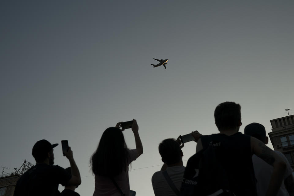 In this photo taken on Wednesday, Aug. 22, 2018 people photograph a military aircraft flying above the city center during a rehearsal for the Independence Day military parade in Kiev, Ukraine. Ukraine will mark the 27th anniversary of the Independence Day on Aug. 24. (AP Photo/Felipe Dana)